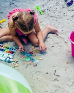 Ella paints seashells on the beach