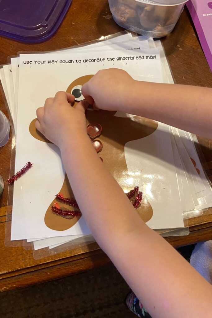 child decorating a play dough gingerbread man