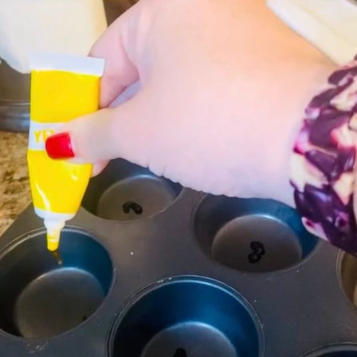 adding food coloring to a muffin tin for sensory play set up