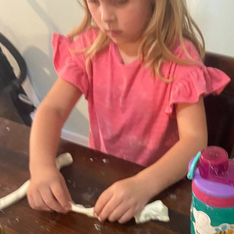 child rolling out cloud dough