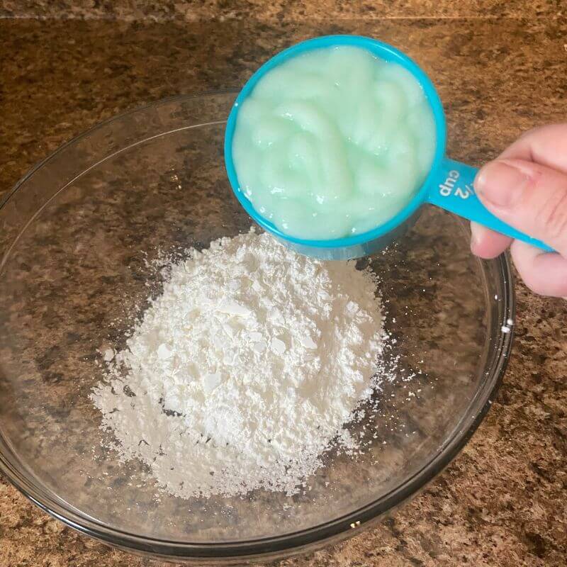 pouring ingredients to make cloud dough