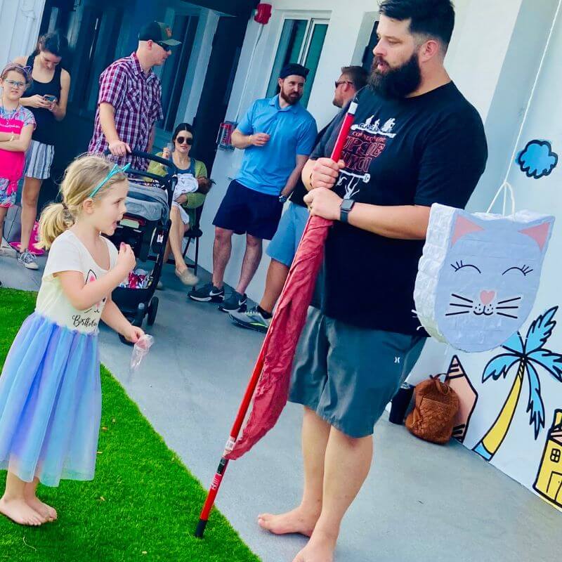 five year old girl getting ready to hit a cat pinata