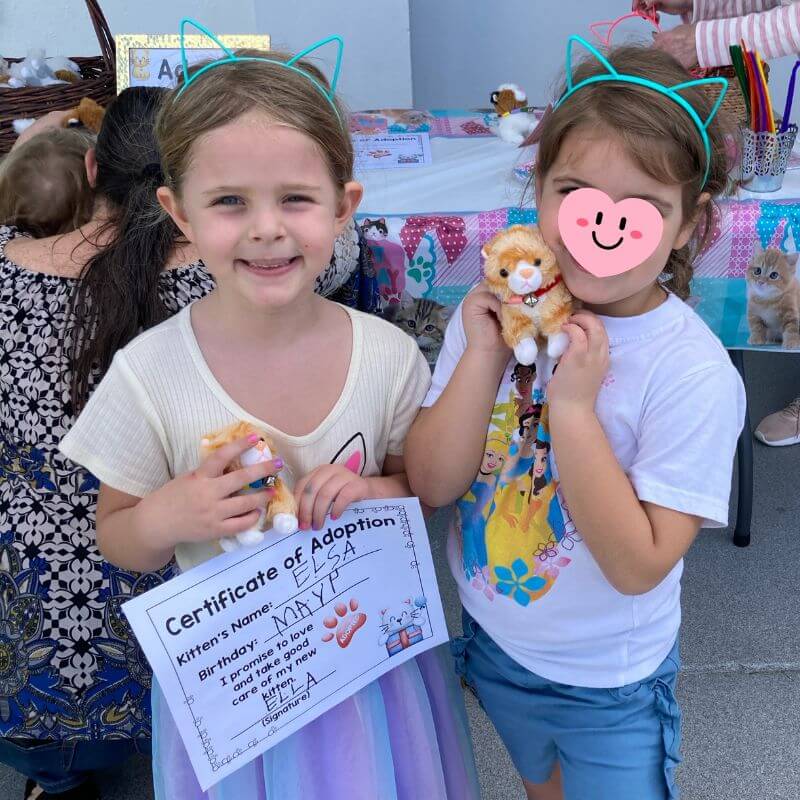 two girls holding a kitty adoption certificate and a stuffed kitty