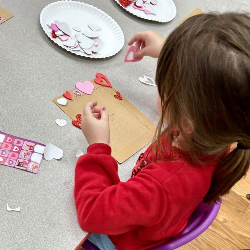 child decorating picture frame with heart stickers