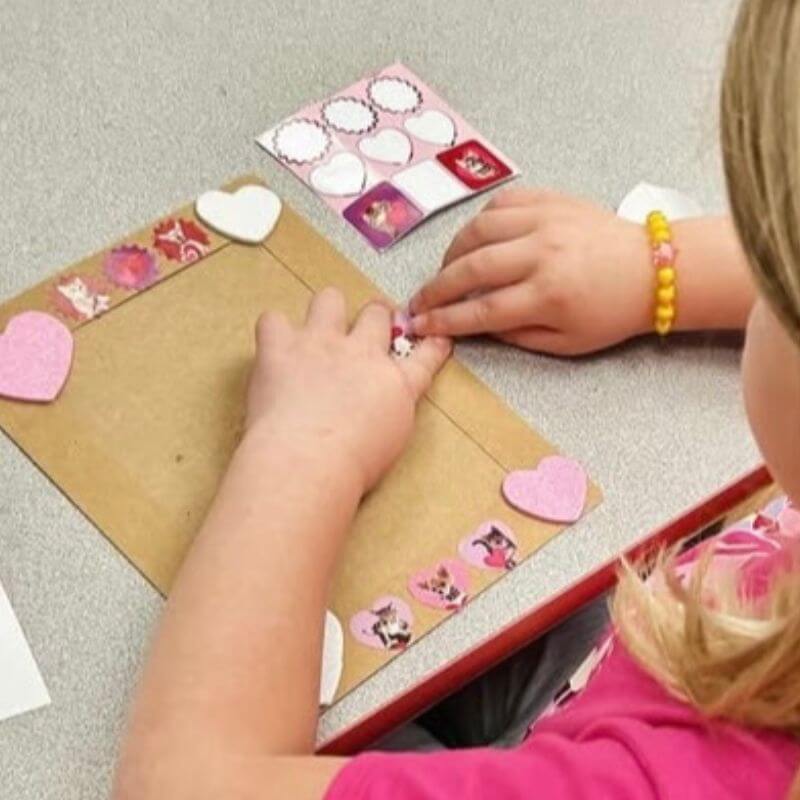 child putting stickers on a picture frame