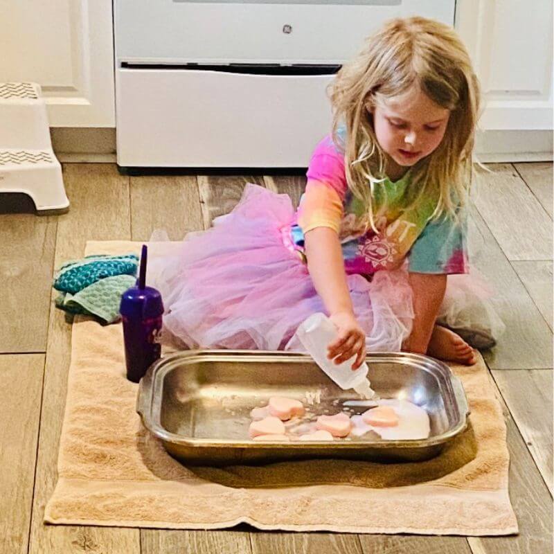 child playing with baking soda fizzy hearts (Valentine's Day STEM activity) 