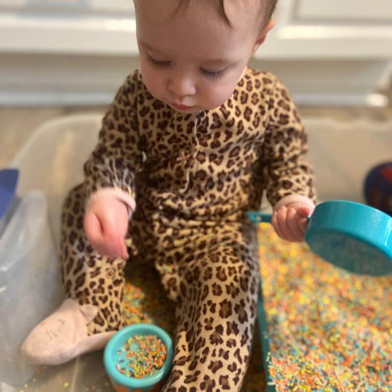 baby playing with rainbow rice