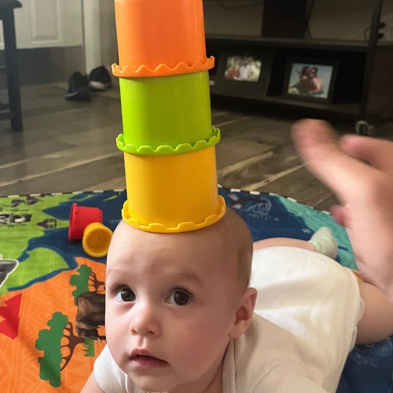 baby with stacking cups on her head