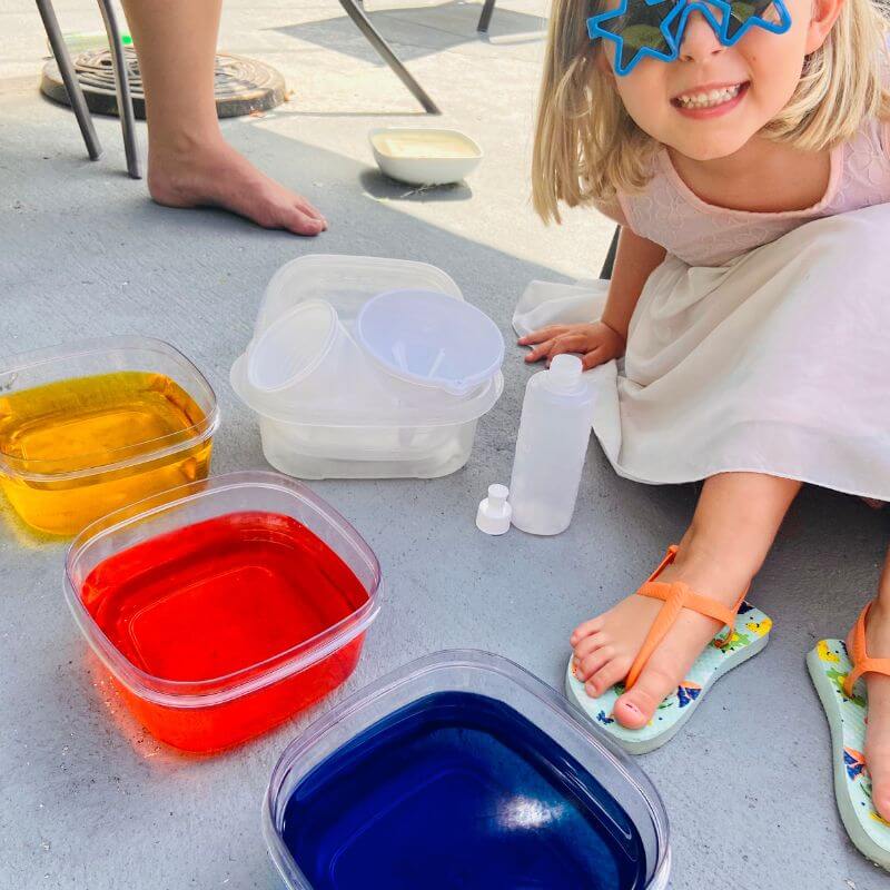 young girl smiling next to color mixing activity