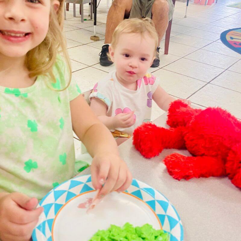 two young girls smiling and tasting green eggs and ham