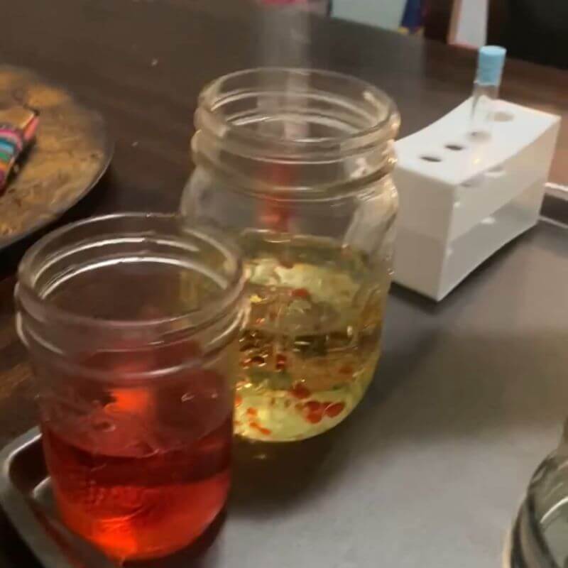 red water being dropped into oil and forming colorful bubbles